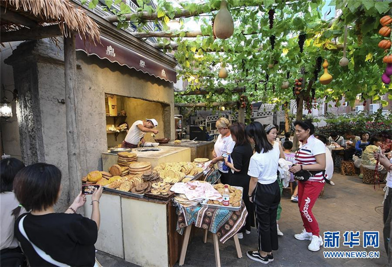 在位于乌鲁木齐市的大巴扎景区，游客购买刚刚烤制好的馕（2019年8月3日摄）。新华社记者 王菲 摄.jpg